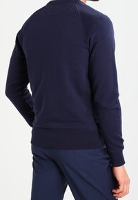Marineblauwe sweatshirt, gemaakt van zachte stof, met een ronde halslijn en geribbelde mouwen. Het ontwerp heeft een ontspannen pasvorm en een gladde textuur.
