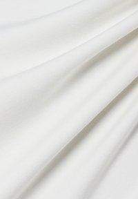 Weißer Baumwollstoff, glatt mit einer leichten Textur, der subtile Falten und Knicke aufweist und ein leichtes und atmungsaktives Erscheinungsbild vermittelt.