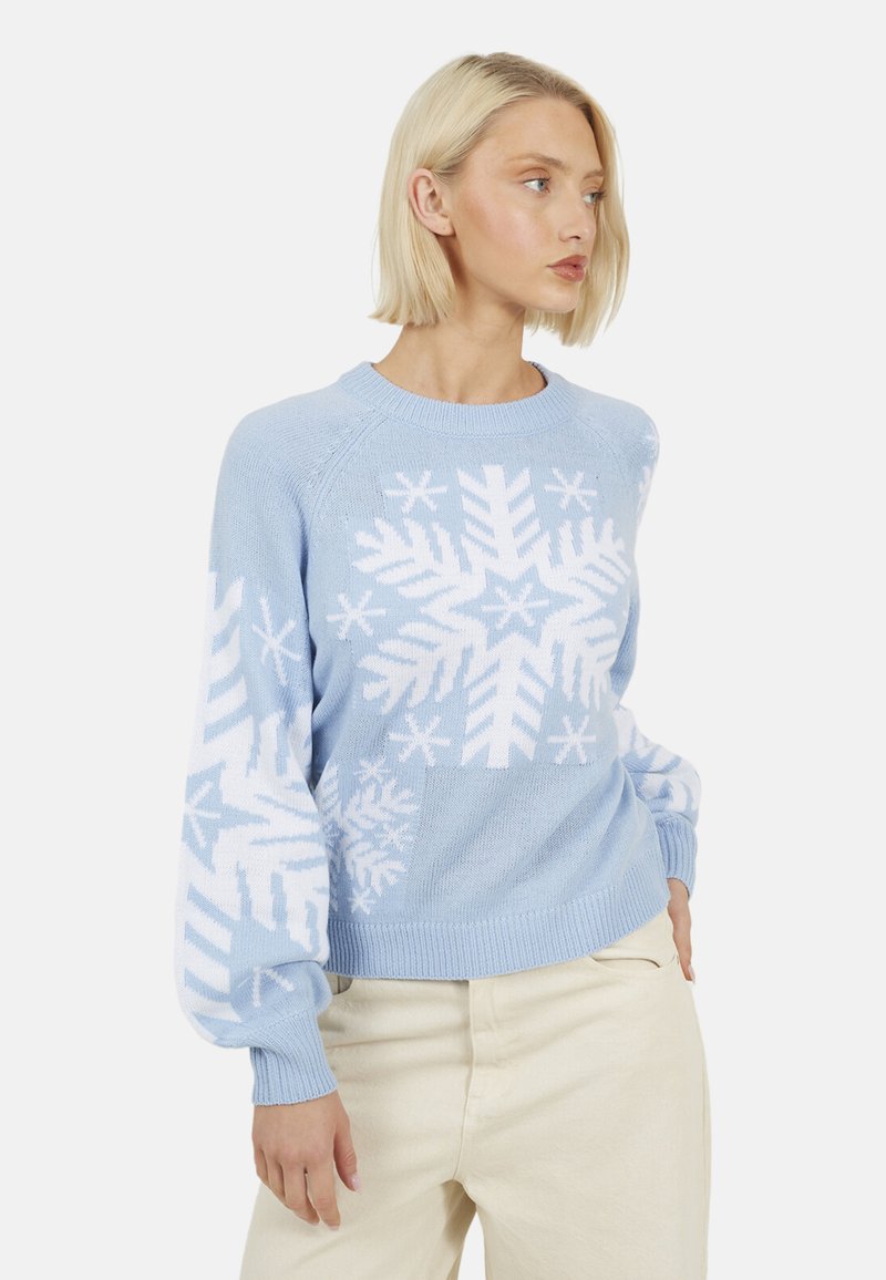 Maglione azzurro chiaro con motivi di fiocchi di neve bianchi, caratterizzato da polsini e scollo a coste. Il disegno è ben visibile sulla parte anteriore e sulle maniche.