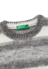 Szary i biały sweter w paski wykonany z dzianiny z prążkowanym dekoltem. Posiada zieloną metkę z napisem "UNITED COLORS OF BENETTON". Miękka tekstura.