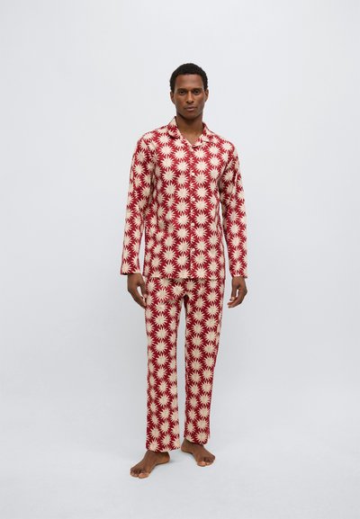 Set de pijama roșu și crem cu mâneci lungi și pantaloni, decorat cu un model de raze stelare, realizat dintr-un material moale și neted.