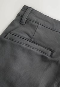 Sive hlače iz tkanine z gladko teksturo, s hrbtnim žepom z znakom šivanja in zanko za pas na pasu.