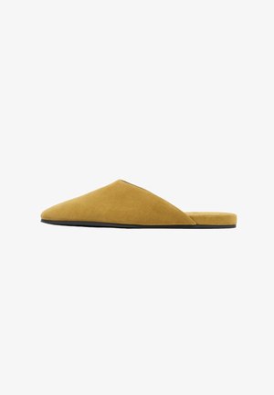 Suedetupsuja keltamustassa, jossa on terävä kärki ja matala musta pohja. Sujuva pinta, minimalistinen tyyli.