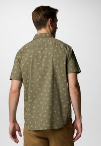 Camicia a maniche corte di colore verde oliva con un motivo di piccole piante e simboli del sole, dotata di colletto button-down e orlo dritto.