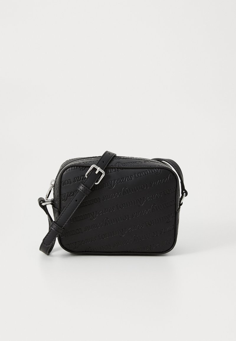 Svart crossbody-veske med preget logomønster, glidelås, justerbar stropp, glatt tekstur og rektangulær form.