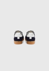 Marineblå semskede sneakers med hvite detaljer, med en teksturert gummisåle og bakre tab med merkevare. Klassisk lavtopp-design.