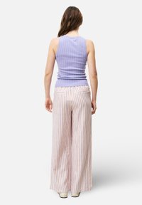 Lavendel geribbelde tanktop gecombineerd met wijde, verticaal gestreepte broek in pastelkleuren van roze, oranje en wit. Soepele textuur, casual pasvorm.