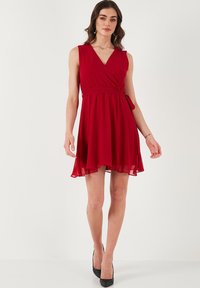 Red wrap dress with a V-neck, sleeveless design, and a flowing A-line skirt; made of lightweight fabric with a tie waist detail.