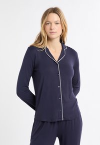 Set di pigiama blu navy con maniche lunghe, colletto a revers e bordatura bianca lungo il colletto e la patta dei bottoni. Tessuto morbido e liscio.