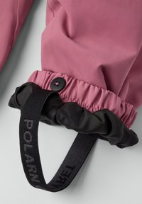 Paarse en zwarte mouw van een jack met elastische gathering, een zwarte knop en een geweven label met "POLARN." Close-up van de textuur van de stof.