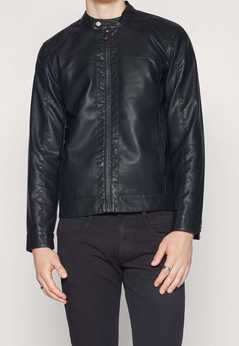 Giacca di pelle nera con colletto alto, zip anteriore e tasche laterali. Texture liscia e design aderente con dettagli cuciti.