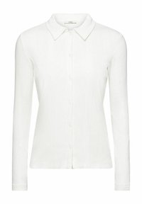 Vit långärmad skjorta med knappar, spetsig krage, ribbad textur och rak skärning vid fållen. Har frontknäppning.