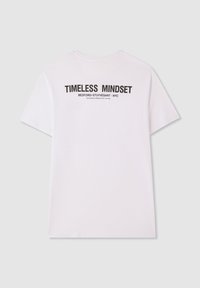 Biała bawełniana koszulka z krótkim rękawem i okrągłym dekoltem. Tekst na plecach brzmi "TIMELESS MINDSET BEDFORD-STUYVESANT - NYC."