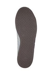 Grå atletisk skosula med ett texturerat gummimönster som har cirkulära grepp och en framträdande varumärkeslogotyp. Platt och bred design.