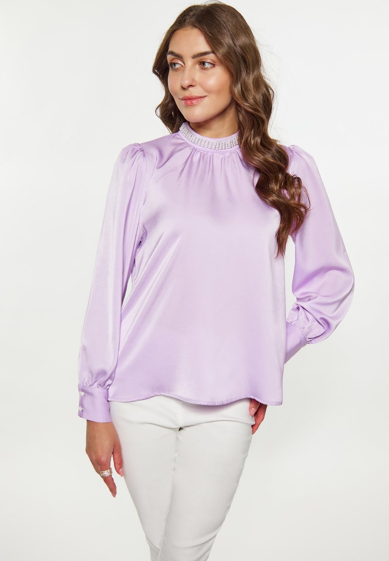 Lila Satinbluse mit Puffärmeln, hohem gerafftem Ausschnitt und Knopfdetails an den Manschetten. Glatte Textur und lockerer Schnitt.