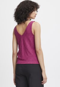 Fuchsia strikket tanktop med V-ryg design, der har et struktureret mønster. Den har brede skulderstropper og en tætsiddende silhuet.