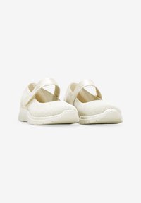 Zapatos de malla blancos con un diseño de tira cruzada, superficie texturizada y suela acolchada. Presentan una estética minimalista y acentos reflectantes de luz.
