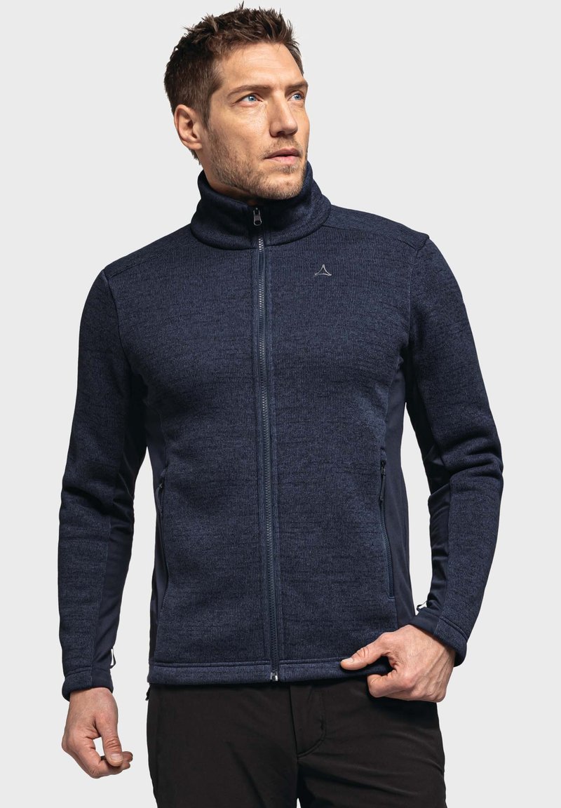 Navy blue fleece zip-up jacket with high collar, side pockets, and textured fabric. Features a logo on the chest and fitted design.