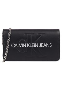 Czarny portfel z ekologicznej skóry z wytłoczonym białym logo „CALVIN KLEIN JEANS”. Posiada srebrny łańcuszek. Prostokątny kształt, gładka faktura.