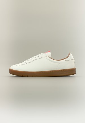 Scarpa da ginnastica bianca bassa con suola marrone, lacci bianchi e dettaglio rosa sulla linguetta, mostrata di lato su sfondo chiaro e neutro.