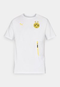 Hvid sports t-shirt med korte ærmer, prydet med et gult BVB-logo, gule accenter og en lynlåslomme på venstre side af forsiden. Letvægtsmateriale.
