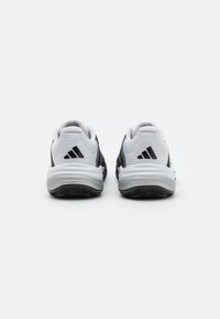 Chaussures de sport noir et blanc avec une tige en maille, semelle en caoutchouc et logo Adidas. Elles présentent un design épuré et un col rembourré.