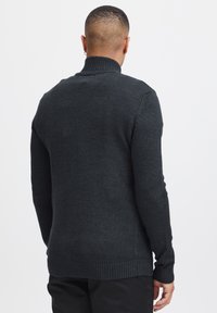 Donkergrijze coltrui met geribbelde halslijn en mouwen, voorzien van een textuur gebreid patroon en een rechte zoom. Achteraanzicht weergegeven.