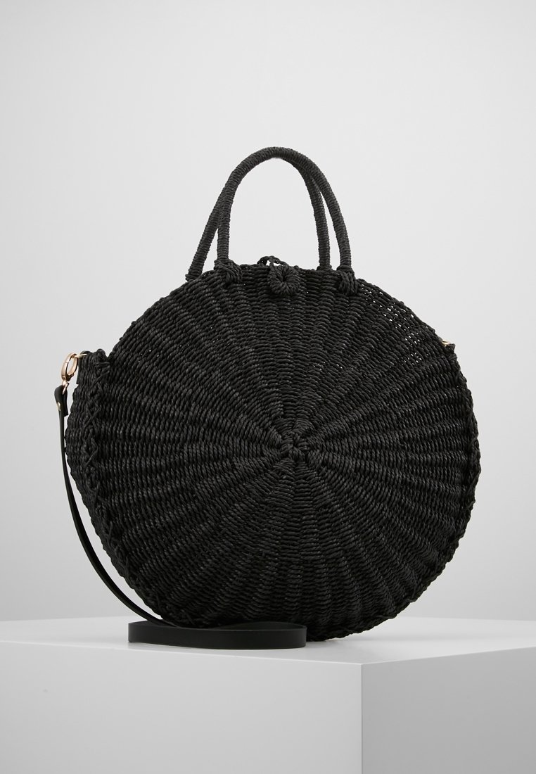 Svart rund vävt väska med två handtag och ett avtagbart rem. Tillverkad av texturerat material med spiral mönster och subtil lyster.