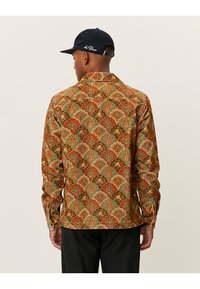 Corduroy skjorte med et flerfarvet geometrisk blomsterdesign. Designet med krave og lange ærmer, har ribbet tekstur og lige nederste kant.