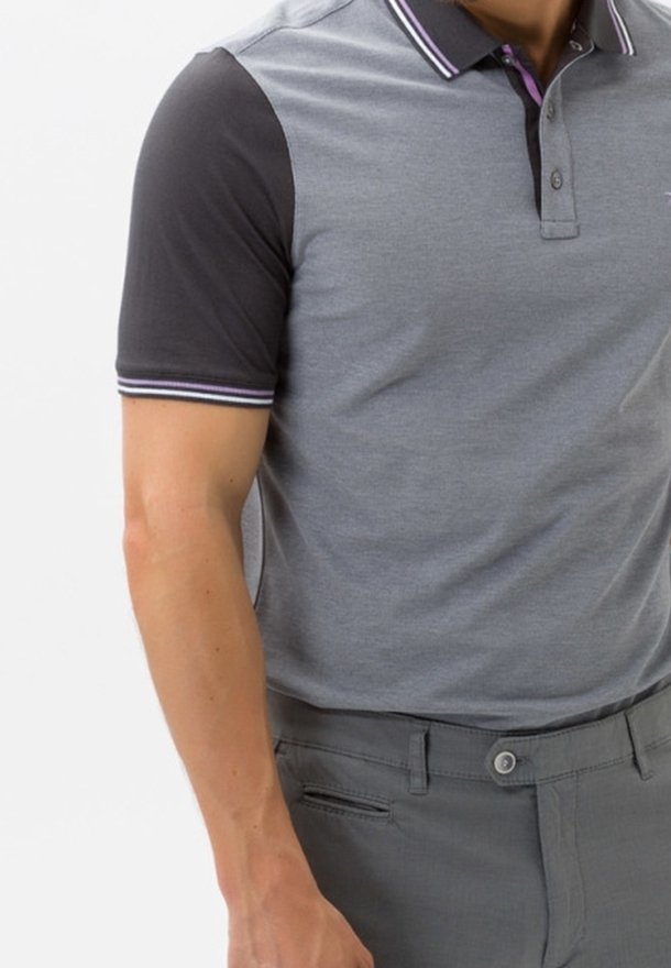 Polo shirt col montant en gris avec des manches courtes noires, présentant de fines accents blancs et violets sur le col. Le matériau semble doux et léger.