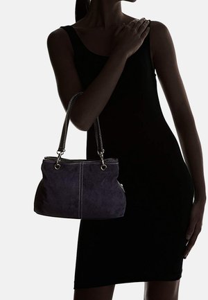 Dunkelviolette Wildlederhandtasche mit silbernem Beschlag, die über doppelte Griffe und kontrastierende weiße Nähte verfügt und eine geschwungene Silhouette zeigt.