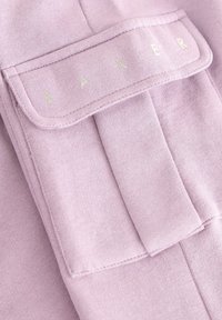Fialová látka so soft, textúrovaným povrchom. Obsahuje klopu s vreckom s nápisom "BAKER" v svetlom písme.