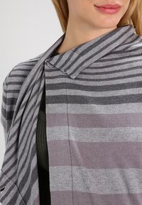 Striped cardigan featuring shades of gray and lilac, crafted from soft fabric, with a shawl collar and open front design showcasing vertical stripes.