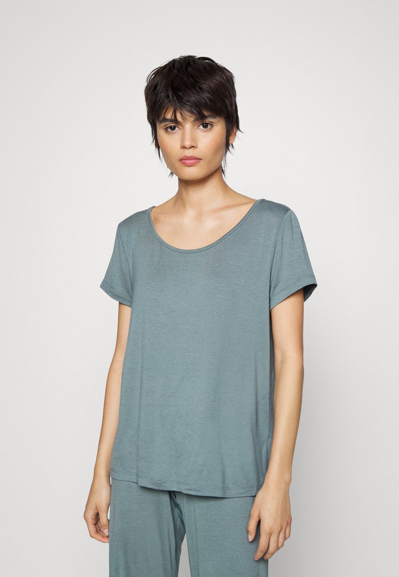 T-shirt court à manches courtes en teal clair avec un décolleté arrondi. Tissu doux, coupe décontractée et texture subtile. Associé avec un pantalon assorti.