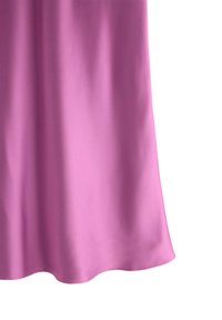 Lyserødt satinstof med bløde folder og en let bølget kant, hængende mod en hvid baggrund.