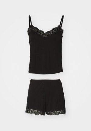 Fekete ujjatlan felső és rövidnadrág szett. A felső csipkés díszítéssel rendelkezik a nyakrésznél, a rövidnadrág pedig csipkés részletekkel a szegély mentén. Puha anyagból készült.