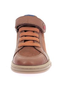 Scarpa alta in pelle marrone con lacci elastici e una cinghia in velcro. Presenta una superficie texturizzata e una suola in gomma beige.