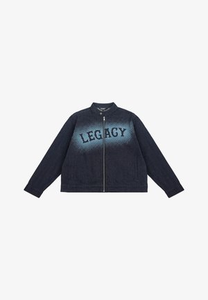 Jaqueta de denim azul escuro com gola alta, fecho de zipper e a palavra "LEGACY" impressa a preto com um efeito de degradê na parte da frente.
