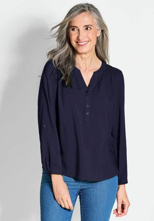 Blusa a maniche lunghe blu navy con scollatura a V e pattina con bottoni; tessuto morbido e liscio con vestibilità rilassata e dettagli arricciati sulle spalle.