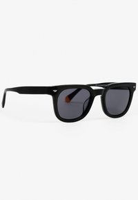 Czarne okulary przeciwsłoneczne o kwadratowej ramie, ciemnych szkłach i eleganckim, matowym wykończeniu. Szczególnym detalem jest mały metalowy akcent na zausznicy.