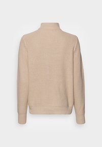 Beige gebreide trui met een hoge kraag, voorzien van een gestructureerd patroon en geribbelde manchetten. De achterkant is glad en heeft een losse pasvorm.