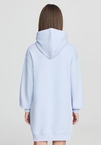Błękitna sukienka z kapturem, z opadającymi ramionami, długimi rękawami i luźnym krojem, charakteryzująca się miękką teksturą i długością do połowy uda.