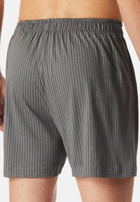 Shorts de bain rayés gris avec une taille élastique, présentant une texture fine et un motif de rayures bleu clair contrastant.