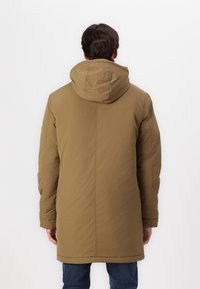 Olijfgroen gewatteerde jas met een capuchon, met een soepele textuur, lange mouwen en eenvoudige naaddetails, die tot halverwege de dij komt.