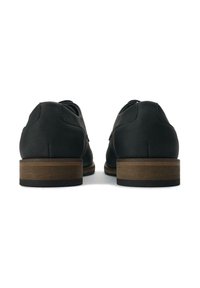 Black leather shoes featuring a rounded shape, flat brown wooden heel, and simple lace-up design. Smooth texture with minimal detailing.