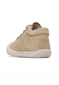 Béžová semišová kotníková obuv s šedými tkaničkami, bílou gumovou podrážkou a strukturovaným podpatkem. Na boku má embosované logo. Hladký a jemný povrch.