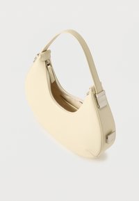 Τσάντα χειρός σε σχήμα ημισελήνου σε κρεμ απόχρωση με ένα λουράκι και ασημένιο φερμουάρ μισάνοιχτο σε λευκό φόντο.