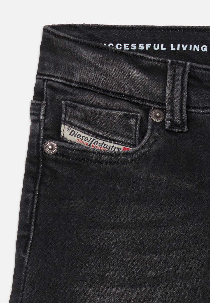 Schwarze Denim-Jeans mit kleiner Fronttasche, die das Diesel Industry-Label zeigt und teilweise sichtbaren Text des Bunds "Successful Living".