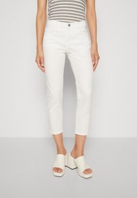 White cropped jeans with a smooth texture and front pockets, paired with white heeled mules featuring a wide strap and thick heel.