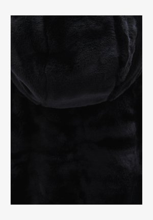 Tissu en fausse fourrure noire avec une texture douce et moelleuse, présentant une finition lisse et une couleur uniforme sur toute la surface.